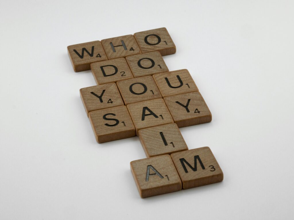 Wooden scrabble tiles arranged to spell 'Who do you say I am' on a white background.