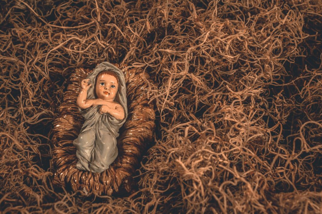 A nativity scene featuring a baby Jesus figurine surrounded by straw, symbolizing hope and tradition.