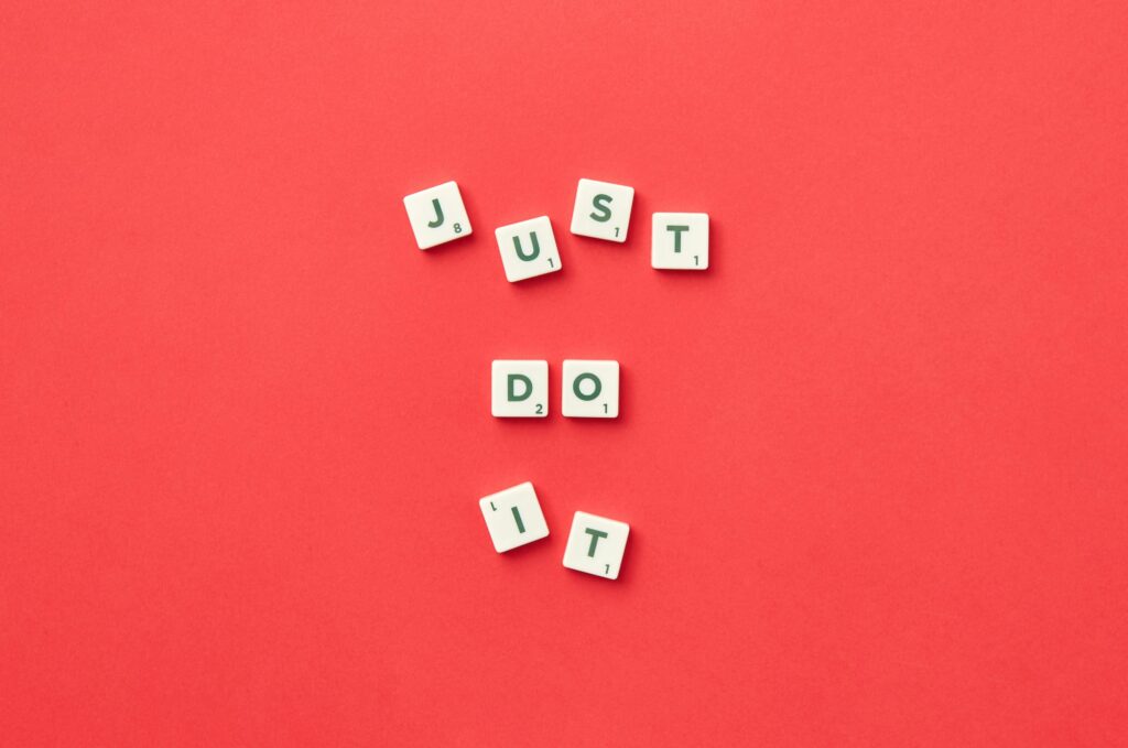 Motivational phrase 'Just Do It' spelled with Scrabble letters on a red background.