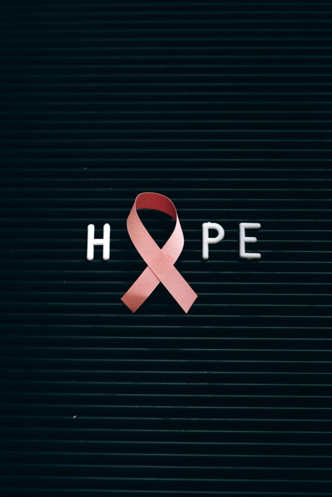 Close-up of a pink ribbon forming the word 'Hope' on a letter board.