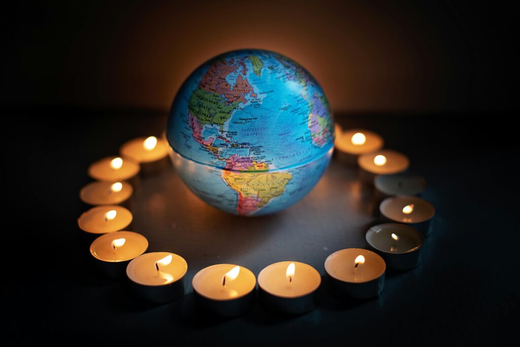 A globe encircled by candlelights symbolizing global unity and peace.