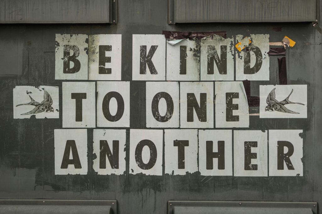 Close-up of 'Be Kind to One Another' message on a weathered background.