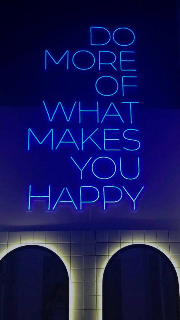 pexels-photo-17275854-17275854 Bright neon sign displaying the motivational phrase 'Do More of What Makes You Happy' against a dark backdrop.