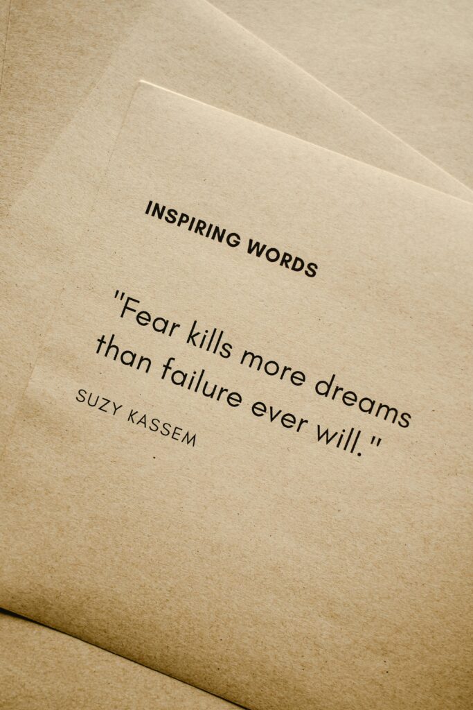 pexels-photo-6956352-6956352 Motivational quote 'Fear kills more dreams than failure ever will.' by Suzy Kassem on paper texture.