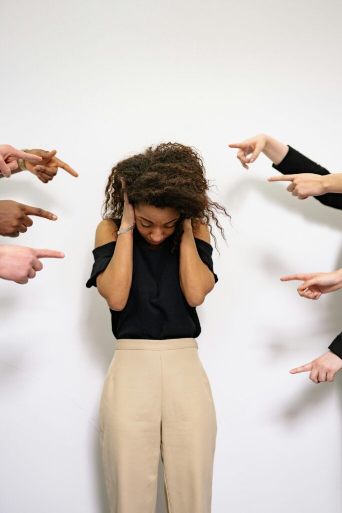 pexels-photo-7640497-7640497 A woman overwhelmed, surrounded by pointing fingers, depicting bullying.