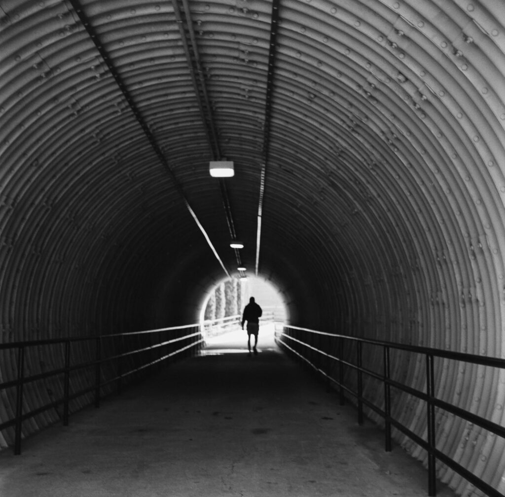 pexels-photo-31373923-31373923 A solitary figure walks through a tunnel in Kennesaw, Georgia, captured in moody black and white.