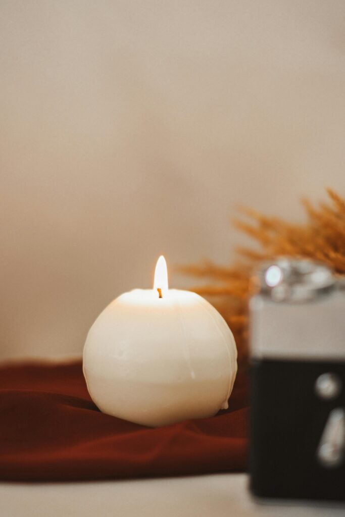 A serene image of a burning spherical candle on a soft fabric for a warm and cozy ambiance.