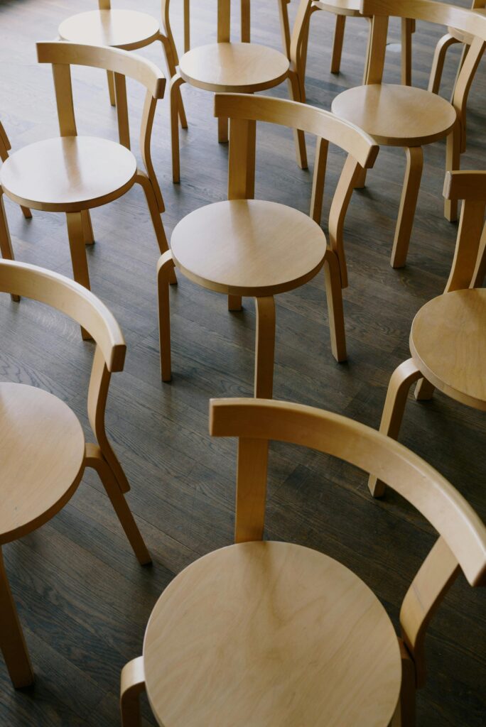 From above of wooden round chairs placed on parquet floor in room for occasion
