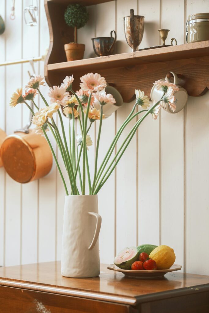 Charming kitchen with daisies in a vase and fresh fruits on the table.