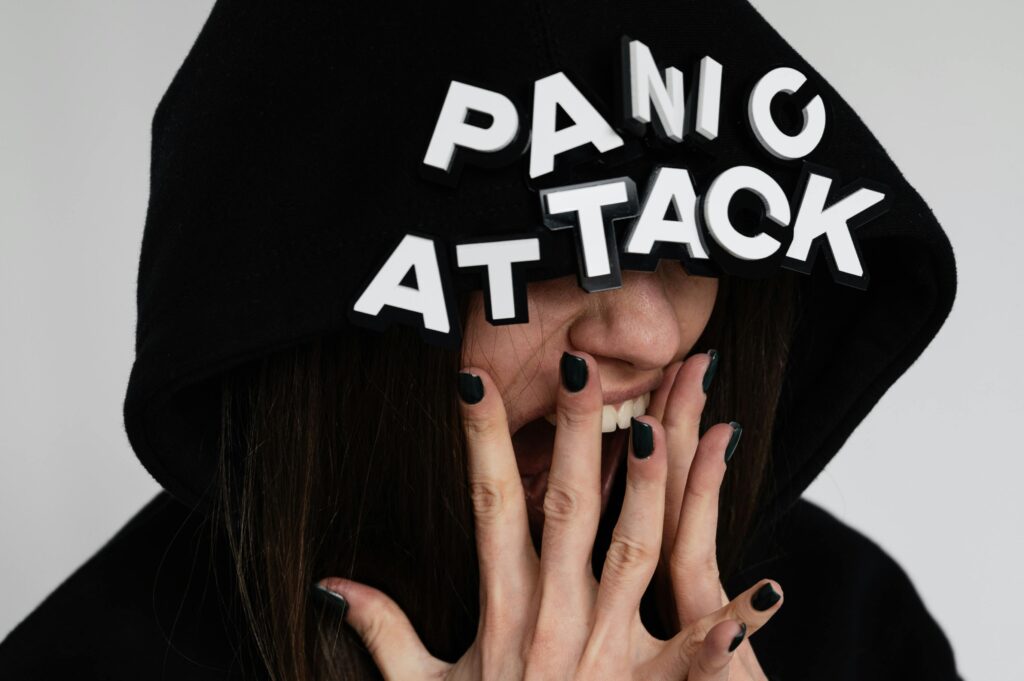 Close-up of a woman in a hoodie with 'panic attack' text, conveying anxiety.